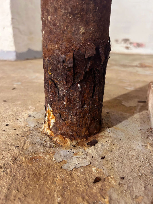 Severe corrosion at the base of a steel lally column in a basement